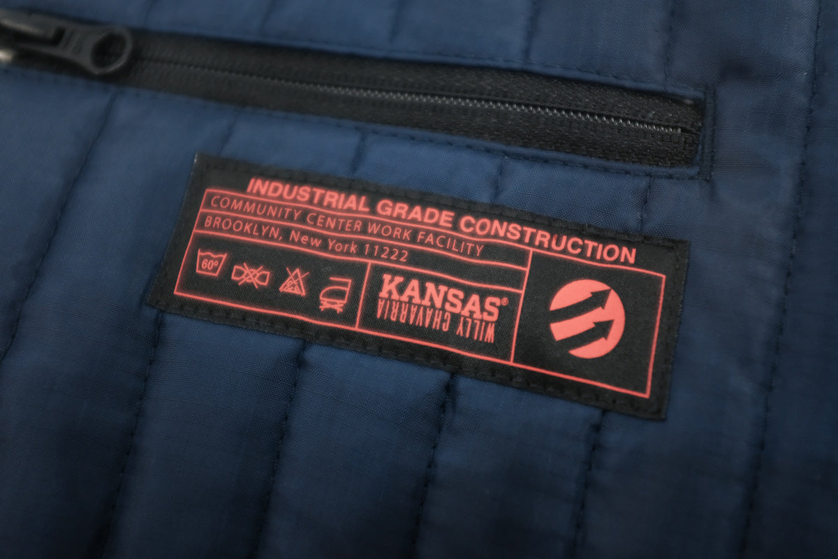 Willy Chavarria X Kansas collaboration Thermo Vest こちらカラーはUNION BLUEと表記されており、何故か不思議と惹かれます。程よく抑えたボリューム感は重ね着しやすいです。KANSAS、ガチな感じでいくのもよし、スマートな感じでいくのもよしです。老舗ワークブランドKansasとのコラボレーションアイテムです。後ろの着丈を調整できるのも面白いです。ロゴ画像。