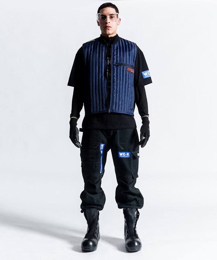 Willy Chavarria X Kansas collaboration Thermo Vest こちらカラーはUNION BLUEと表記されており、何故か不思議と惹かれます。程よく抑えたボリューム感は重ね着しやすいです。KANSAS、ガチな感じでいくのもよし、スマートな感じでいくのもよしです。老舗ワークブランドKansasとのコラボレーションアイテムです。後ろの着丈を調整できるのも面白いです。モデル着用画像。